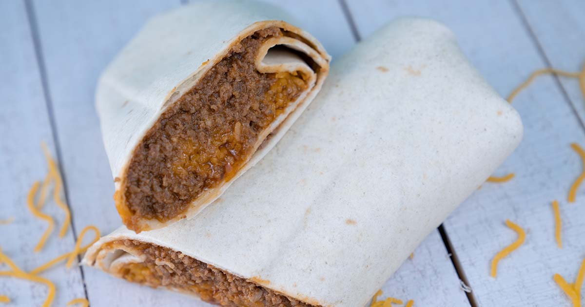 Bean and cheese burrito with beef in a flour tortilla cut in half